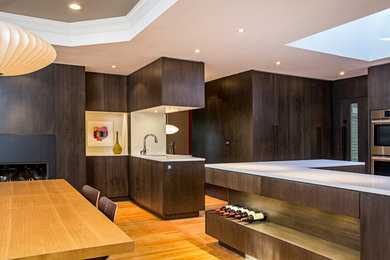 Inspiration for a mid-sized modern u-shaped eat-in kitchen in Atlanta with an undermount sink, flat-panel cabinets, dark wood cabinets, quartz benchtops, white splashback, stone slab splashback, stainless steel appliances, light hardwood floors, a peninsula and brown floor.