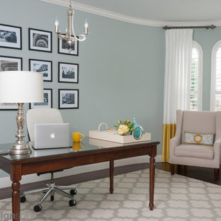 Inredning av ett modernt mellanstort arbetsrum, med gröna väggar, mörkt trägolv och ett fristående skrivbord