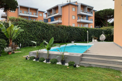 This is an example of a medium sized contemporary back rectangular above ground swimming pool in Rome with a bbq area and natural stone paving.