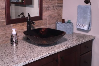 Mid-sized transitional 3/4 brown tile and porcelain tile porcelain tile and beige floor bathroom photo in Chicago with recessed-panel cabinets, dark wood cabinets, beige walls, a vessel sink and granite countertops