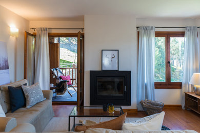 На фото: большая гостиная комната в стиле кантри с бежевыми стенами, печью-буржуйкой, ковром на полу и паркетным полом среднего тона с