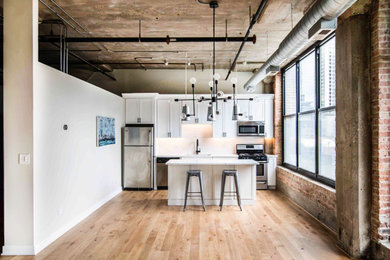 Inspiration for a modern single-wall light wood floor eat-in kitchen remodel in Chicago with an undermount sink, recessed-panel cabinets, white cabinets, quartzite countertops, white backsplash, ceramic backsplash, stainless steel appliances, an island and white countertops