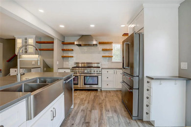 Eat-in kitchen - mid-sized transitional u-shaped brown floor eat-in kitchen idea in Denver with a double-bowl sink, shaker cabinets, white cabinets, quartz countertops, white backsplash, ceramic backsplash, stainless steel appliances, a peninsula and gray countertops