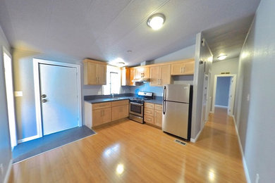 Open concept kitchen - small traditional l-shaped light wood floor and beige floor open concept kitchen idea in San Francisco with an undermount sink, shaker cabinets, light wood cabinets, laminate countertops, gray backsplash, stone slab backsplash, stainless steel appliances and no island