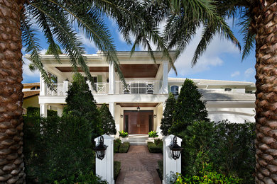 Inspiration for a tropical beige two-story exterior home remodel in Miami with a hip roof