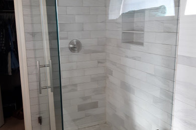 Mid-sized transitional 3/4 gray tile and porcelain tile vinyl floor, brown floor, double-sink and vaulted ceiling bathroom photo with beaded inset cabinets, blue cabinets, white walls, an undermount sink, quartz countertops, a hinged shower door, gray countertops, a niche and a built-in vanity