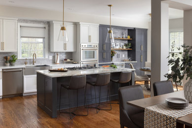 Example of a large transitional l-shaped medium tone wood floor and brown floor eat-in kitchen design in DC Metro with a farmhouse sink, shaker cabinets, gray cabinets, gray backsplash, ceramic backsplash, stainless steel appliances, an island, gray countertops and quartzite countertops