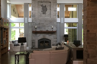 Family room - large transitional open concept medium tone wood floor and brown floor family room idea in Toronto with beige walls, a standard fireplace, a stone fireplace and a media wall