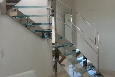 Exemple d'un escalier courbe moderne de taille moyenne avec des marches en verre et un garde-corps en métal.