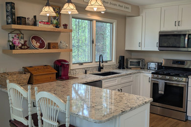 Small transitional u-shaped brown floor eat-in kitchen photo in Other with an undermount sink, flat-panel cabinets and stainless steel appliances