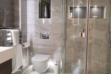 This is an example of a mid-sized contemporary master bathroom in Other with flat-panel cabinets, dark wood cabinets, a corner shower, a wall-mount toilet, gray tile, porcelain tile, grey walls, porcelain floors, a wall-mount sink, grey floor and a hinged shower door.