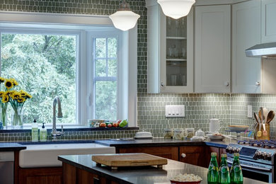 Kitchen - mid-sized modern u-shaped slate floor kitchen idea in New York with a farmhouse sink, shaker cabinets, medium tone wood cabinets, granite countertops, glass tile backsplash, stainless steel appliances and an island