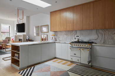 Inspiration for a mid-sized modern u-shaped light wood floor and beige floor open concept kitchen remodel in New York with an undermount sink, flat-panel cabinets, light wood cabinets, quartzite countertops, multicolored backsplash, stone slab backsplash, white appliances, no island and multicolored countertops