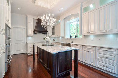 Example of a minimalist l-shaped medium tone wood floor eat-in kitchen design in Vancouver with raised-panel cabinets, white cabinets, an island, a farmhouse sink, granite countertops, stainless steel appliances, white backsplash and ceramic backsplash