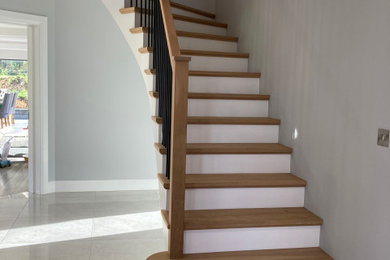 Modern wood curved wood railing staircase in Other with concrete risers.