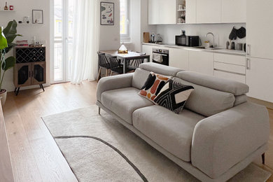 Immagine di un piccolo soggiorno design chiuso con libreria, pareti bianche e parquet chiaro