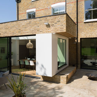 ロンドンのコンテンポラリースタイルのおしゃれな三階建ての家 (レンガサイディング、黄色い外壁、戸建、混合材屋根) の写真