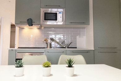 Inspiration pour une petite cuisine ouverte linéaire minimaliste avec un évier encastré, des portes de placards vertess, un plan de travail en stratifié, une crédence grise, un électroménager en acier inoxydable, sol en stratifié, aucun îlot et un plan de travail blanc.