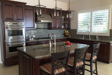 Kitchen - transitional kitchen idea in Los Angeles with raised-panel cabinets, brown cabinets, granite countertops, glass sheet backsplash and an island