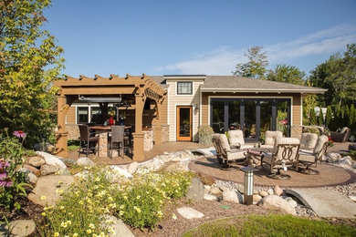 Photo of a mid-sized transitional backyard patio in Other with an outdoor kitchen, tile and a pergola.
