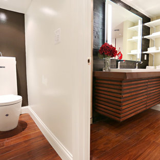 Exemple d'une salle de bain tendance de taille moyenne avec une grande vasque, un placard en trompe-l'oeil, des portes de placard en bois brun, un plan de toilette en cuivre, une baignoire encastrée, une douche ouverte, un WC à poser, un carrelage noir, un carrelage de pierre, un mur beige et un sol en bois brun.