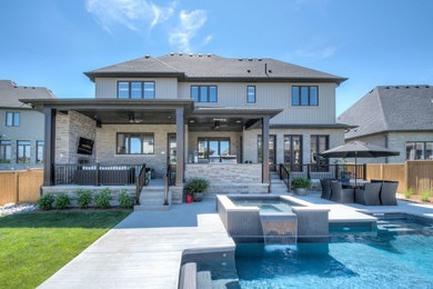 Large backyard concrete and rectangular hot tub photo in Toronto