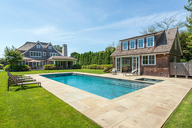 Photo of a large transitional backyard rectangular lap pool in New York with a pool house and concrete pavers.