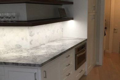 Mid-sized transitional light wood floor and brown floor enclosed kitchen photo in San Diego with shaker cabinets, white cabinets, quartz countertops, gray backsplash, ceramic backsplash and stainless steel appliances