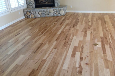 Inspiration for a large rustic open concept medium tone wood floor living room remodel in Boise with beige walls, a corner fireplace, a stone fireplace and no tv