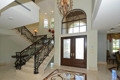 Inspiration for a large mediterranean front door in Miami with beige walls, ceramic floors, a double front door, a glass front door and beige floor.
