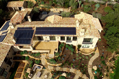 Large tuscan beige three-story stone house exterior photo in Santa Barbara with a tile roof