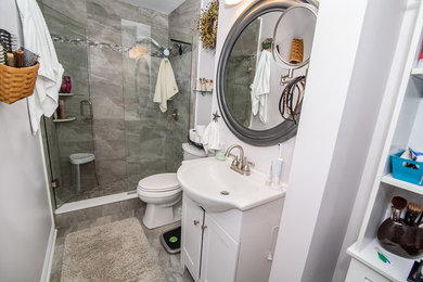 Inspiration for a mid-sized transitional 3/4 white tile and porcelain tile marble floor and gray floor alcove shower remodel in Other with shaker cabinets, white cabinets, a two-piece toilet, white walls, a drop-in sink, quartz countertops and a hinged shower door