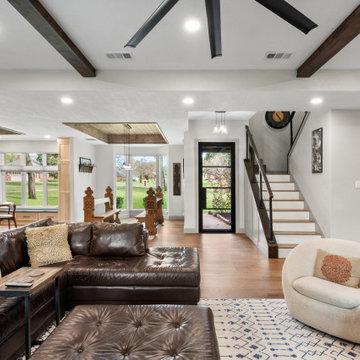 Open-concept living room with leather sectional and wood ceiling beams.