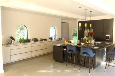 Design ideas for a large contemporary open plan kitchen in Surrey with flat-panel cabinets, black cabinets, granite worktops, concrete flooring, grey floors, black worktops, a vaulted ceiling and feature lighting.