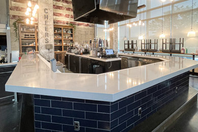 Photo of an expansive modern u-shaped breakfast bar in Baltimore with engineered stone countertops, concrete flooring, black floors and grey worktops.