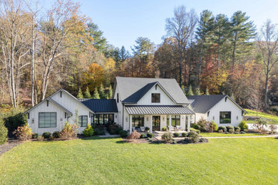Country white two-story concrete fiberboard and board and batten exterior home idea in Other with a mixed material roof and a black roof