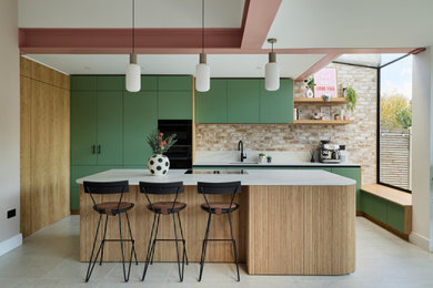This is an example of a medium sized contemporary l-shaped open plan kitchen in London with flat-panel cabinets, green cabinets, engineered stone countertops, an island and white worktops.