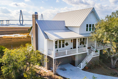 This is an example of a large transitional two-storey white house exterior in Charleston with a gable roof and a metal roof.