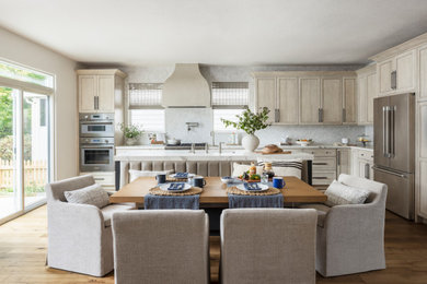 Mid-sized transitional l-shaped medium tone wood floor open concept kitchen photo in Denver with a single-bowl sink, recessed-panel cabinets, light wood cabinets, solid surface countertops, white backsplash, marble backsplash, stainless steel appliances, an island and white countertops