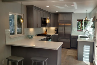 Inspiration for a small contemporary u-shaped light wood floor open concept kitchen remodel in San Francisco with an undermount sink, shaker cabinets, gray cabinets, quartz countertops, white backsplash, glass tile backsplash, stainless steel appliances and a peninsula