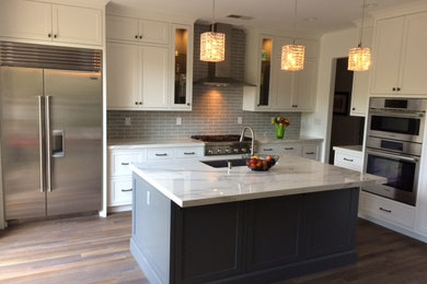 Inspiration for a large modern l-shaped medium tone wood floor and brown floor eat-in kitchen remodel in San Diego with a drop-in sink, shaker cabinets, white cabinets, marble countertops, gray backsplash, ceramic backsplash, stainless steel appliances and an island