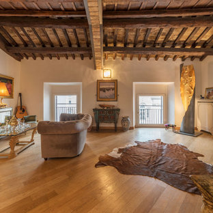 Immagine di un soggiorno mediterraneo con pareti beige, pavimento in legno massello medio, TV a parete e pavimento marrone