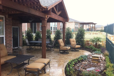 Mid-sized traditional backyard patio in Dallas with natural stone pavers and a roof extension.