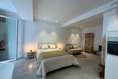 Imagen de dormitorio tipo loft mediterráneo de tamaño medio con paredes blancas y suelo gris