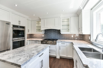 Inspiration for a timeless medium tone wood floor and brown floor kitchen remodel in Toronto with an undermount sink, white cabinets, quartzite countertops, gray backsplash, glass tile backsplash, stainless steel appliances, an island and gray countertops