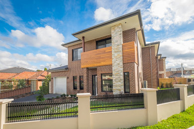 Large modern two-storey multi-coloured exterior in Sydney with stone veneer, a hip roof and a tile roof.