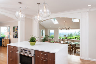 Open concept kitchen - mid-sized coastal l-shaped medium tone wood floor open concept kitchen idea in Portland with flat-panel cabinets, medium tone wood cabinets, quartz countertops, subway tile backsplash, stainless steel appliances, an island and white countertops