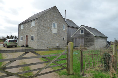 Photo of a medium sized and gey traditional two floor rear house exterior in Wiltshire with mixed cladding, a tiled roof and a grey roof.