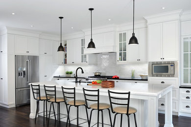 Example of a mid-sized transitional l-shaped dark wood floor kitchen pantry design in Toronto with an undermount sink, shaker cabinets, white cabinets, quartz countertops, white backsplash, subway tile backsplash, stainless steel appliances and an island
