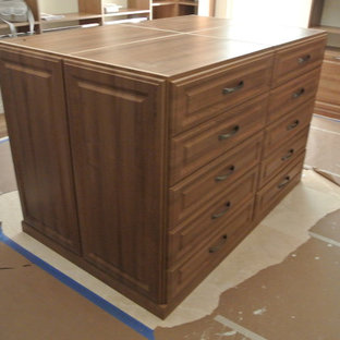 This is an example of a large classic gender neutral dressing room in Miami with raised-panel cabinets, medium wood cabinets and travertine flooring.